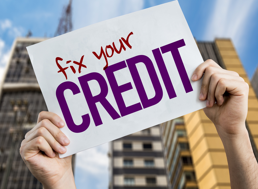 A woman holding a sign that says: "Fix your credit"